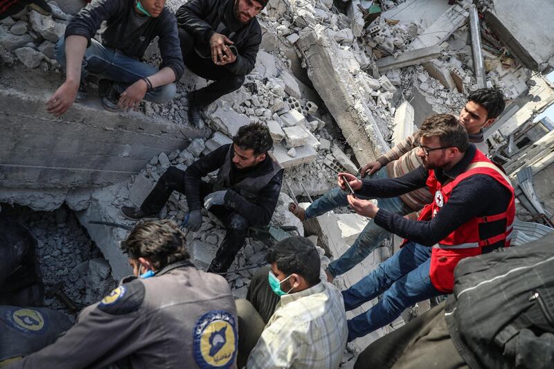 epa06584771 A volunteer with International Committee of the Red Cross photographs Civil defense rescuers searching for a body of victim under a collapsed building that was targeted by a strike on 22 February, after they were called to look for the victim buried under the rubbles in Douma, Syria, 05 March 2018 (issued 06 March 2018). Syrians in the neighborhood failed to reach the body of victim since the building collapsed on 22 February and on 05 March alerted the civil defense members to the possible place the body of the victim was trapped under the rubble as a convoy of the UN, Red Cross and Syrian Arab Red Crescent entered eastern Ghouta to deliver humanitarian aid.  EPA/MOHAMMED BADRA