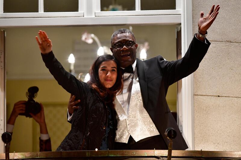Nobel prize laureates Congolese gynecologist Denis Mukwege (R) and Iraqi Yazidi-Kurdish human rights activist Nadia Murad greet the crowd from the balcony of the Nobel suite in Oslo downtown, Norway on December 10, 2018. (Photo by Tobias SCHWARZ / AFP)