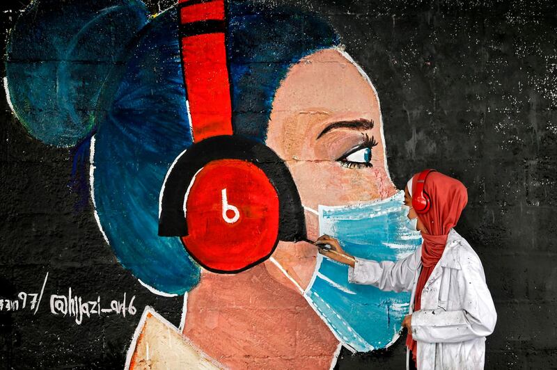 A Palestinian artist paints a mural of a mask-clad schoolgirl in Gaza City. AFP