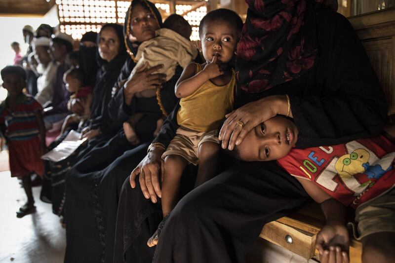 BALUKHALI, BANGLADESH - AUGUST 27: Women and children are seen waiting to be treated in the Médecins Sans Frontières/Doctors Without Borders (MSF) clinic on August 27, 2018 in Balukhali camp, Cox's Bazar, Bangladesh. UN investigators said on Monday that Myanmars army had carried out genocide against the Rohingya in Rakhine state and that its top military figures must be investigated for crimes against minorities across the country. The UN report accused Myanmars military for murders, imprisonments, enforced disappearances, torture, rapes and other forms of sexual violence in Rakhine state, all of which constitute crimes against humanity, as a wave of violence forced more than 720,000 Rohingya to flee into the Coxs Bazar district of Bangladesh one year ago. (Photo by Paula Bronstein/Getty Images)