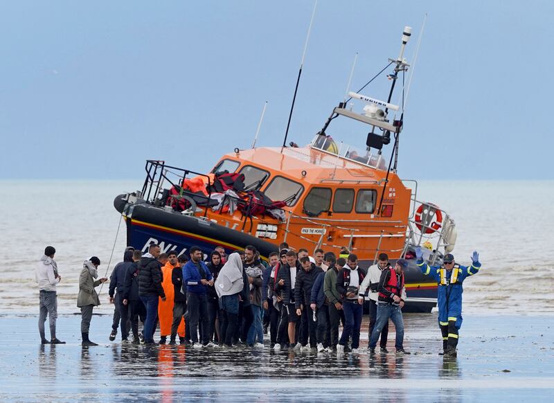 Migrants walk ashore in Dungeness, Kent, after being rescued from the English Channel by the Dungeness Lifeboat on Thursday. PA