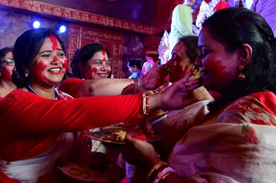 Hindu woman smear vermilion on each other's faces before the immersion of the Goddess Durga in Mumbai on Wednesday.  AFP