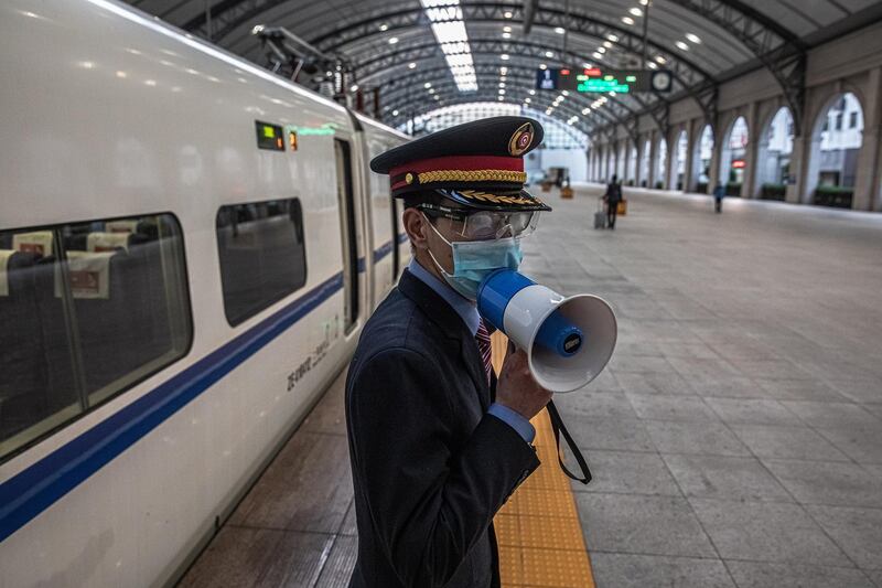 A railway worker speaks in a loudspeaker next to the first official train departing from a railway station after the lockdown was lifted in Wuhan, China.  EPA