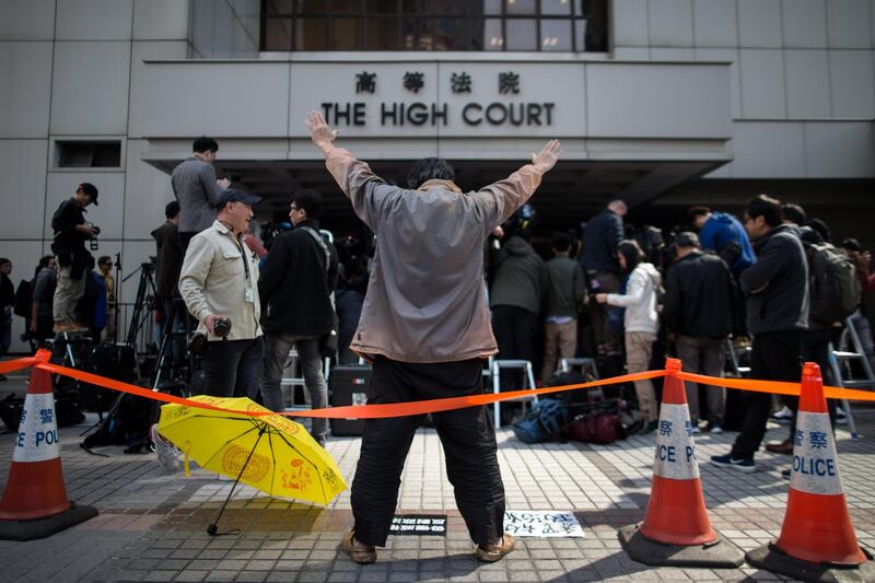 A pro-democracy supporter with a yellow umbrella shouts slogans outside the High Court in Hong Kong. Jerome Favre / EPA