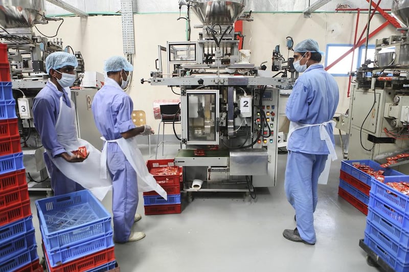 Workers oversee the manufacturing of tomato paste packets at the Chilly Willy manufacturing facility in Dubai.