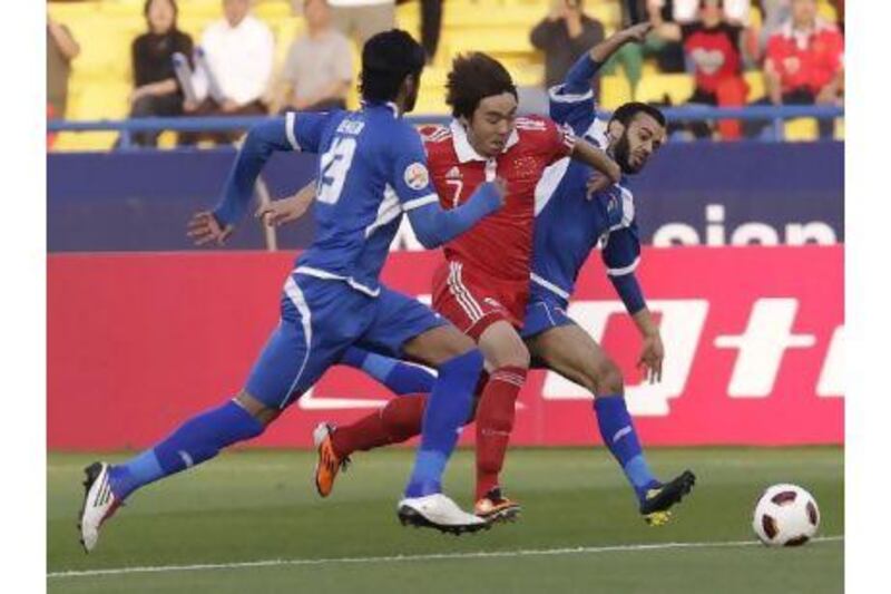 China's Zhao Xuri, in red, vies for the ball with two Kuwaiti players. China kicked off their Asian Cup campaign with a 2-0 win over Kuwait yesterday to boost their hopes of reaching the knockout stages. Hussein Malla / AP Photo
