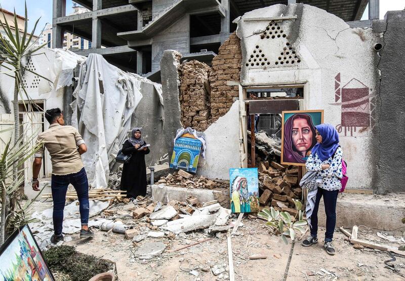 Palestinian artists display artwork in the yard of the damaged Arts and Crafts Village, which was hit by Israeli air strikes two days before, in Gaza City on July 16, 2018.  / AFP / SAID KHATIB
