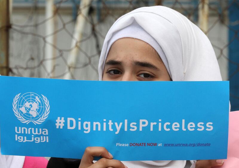 A Palestinian refugee holds a placard at a school belonging to the United Nations Relief and Works Agency for Palestinian Refugees (UNRWA) in the town of Sebline east of the southern Lebanese port of Saida, on March 12, 2018, during a protest against US aid cuts to the organisation.  / AFP PHOTO / Mahmoud ZAYYAT