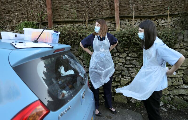 Nurses Elspeth Huber and Rebecca Lock from Hannage Brook Medical Centre put on disposable aprons as they arrive to visit a patient to administer the Covid-19 vaccine during home visits in Derbyshire, England. Reuters