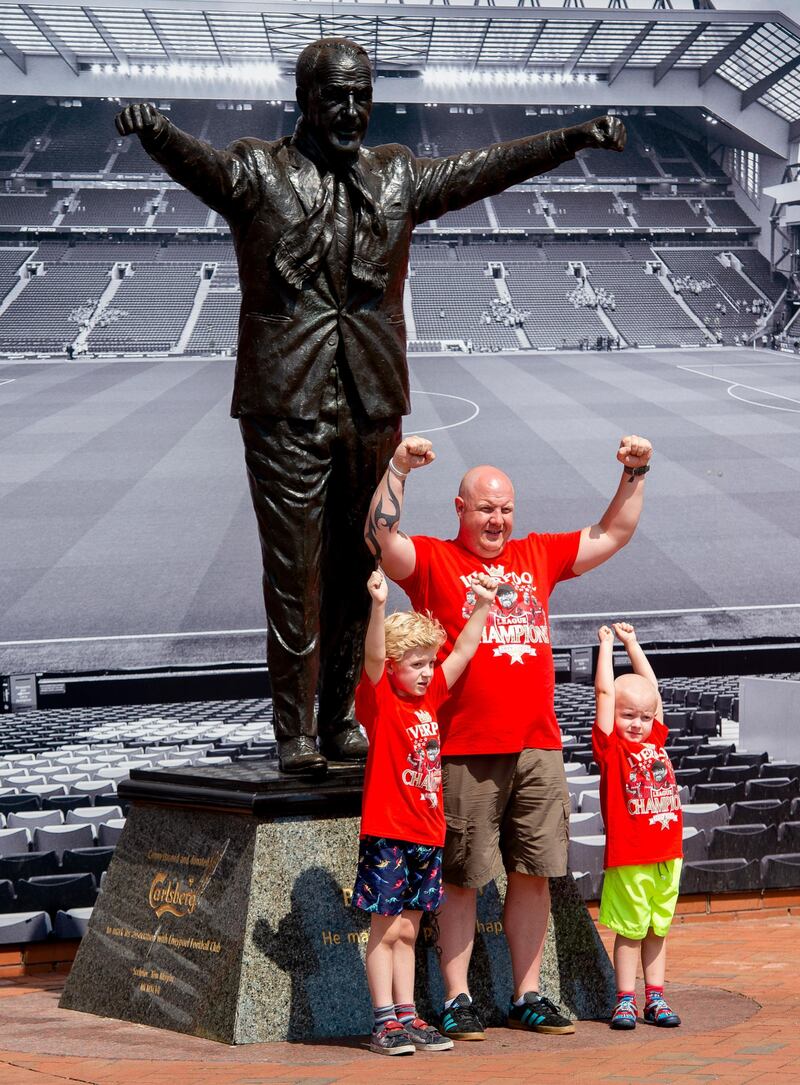 Liverpool fans from different generations pose next to the statue of legendary former Liverpool manager Bill Shankly outside Anfield. EPA