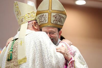 Bishop Paolo Martinelli  is congratulated by outgoing bishop Paul Hinder. Chris Whiteoak / The National