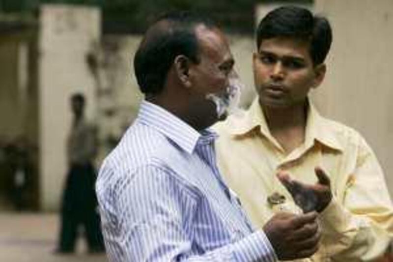 A man smoking within a commercial premise is chided by a social activist in Mumbai, India, Friday, Oct. 3, 2008. India banned smoking in public places on Thursday, leaving public health officials with a much tougher task: persuading the nation's estimated 120 million smokers to stub out their cigarettes. Social activists along with the police kept a strict vigil to enforce the no-smoking law. (AP Photo/ Rajanish Kakade)