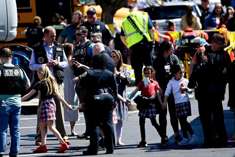 School pupils hold hands after getting off a bus to meet their parents at the reunification site. Reuters