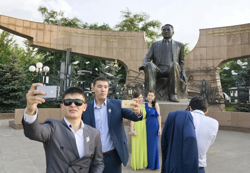 Graduates pose and take pictures in front of a statue of Kazakh President Nursultan Nazarbayev at the First President's Park in Almaty, Kazakhstan, July 3, 2015. Kazakhstan's veteran leader Nursultan Nazarbayev celebrates his 75th birthday on Monday, in good shape and vastly popular, but fireworks and official fanfare can ill hide questions about the future of the second-largest post-Soviet economy. Picture taken July 3. REUTERS/Shamil Zhumatov