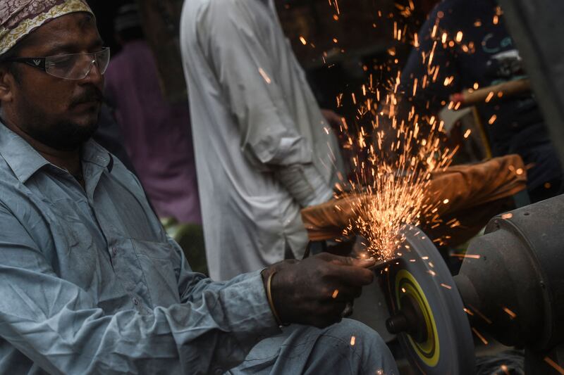 A blacksmith sharpens a knife at his shop in Karachi, Pakistan, before Eid Al Adha.