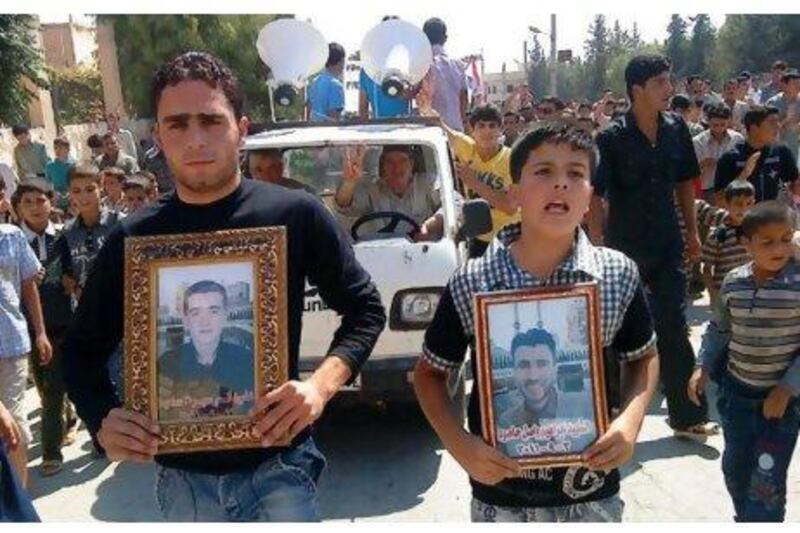 Syrian protesters hold portraits for their dead relatives killed in recent violence as they march in Maaret Harma village yesterday.