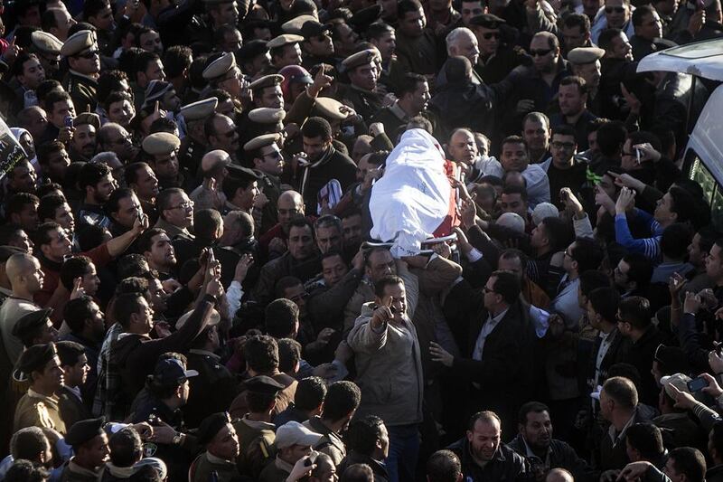 Egyptians carry the body of a policeman who was killed along with 15 other people in a suicide bombing of the police headquarters in Mansoura. Mahmoud Khaled / AFP



