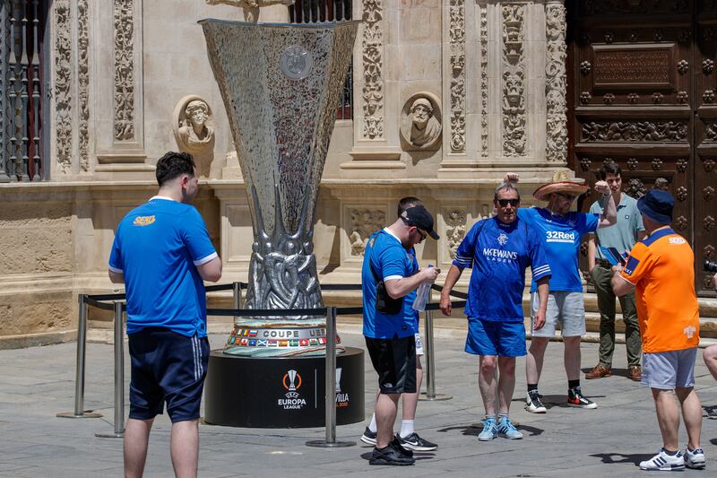 Rangers fans take photographs in front of a giant replica of the Europa League trophy in central Seville. EPA