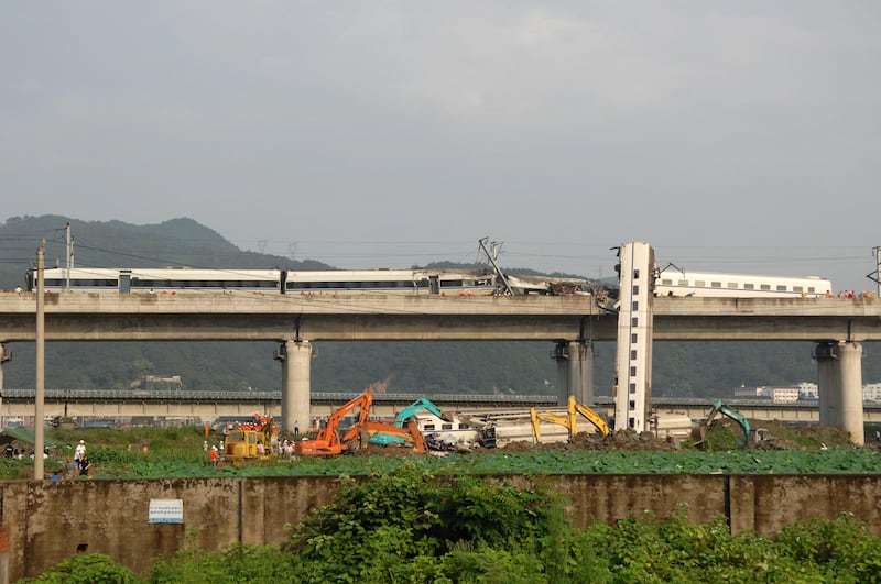 In this photo released by China's Xinhua news agency, a train car leans against a viaduct after falling by an accident in Wenzhou, eastern China, Sunday, July 24, 2011. A Chinese bullet train crashed into another high-speed train that had stalled after being struck by lightning Saturday, causing four carriages to fall off the viaduct. (AP Photo/Xinhua, Ju Huanzong) NO SALES *** Local Caption ***  China Train Crash.JPEG-061fa.jpg