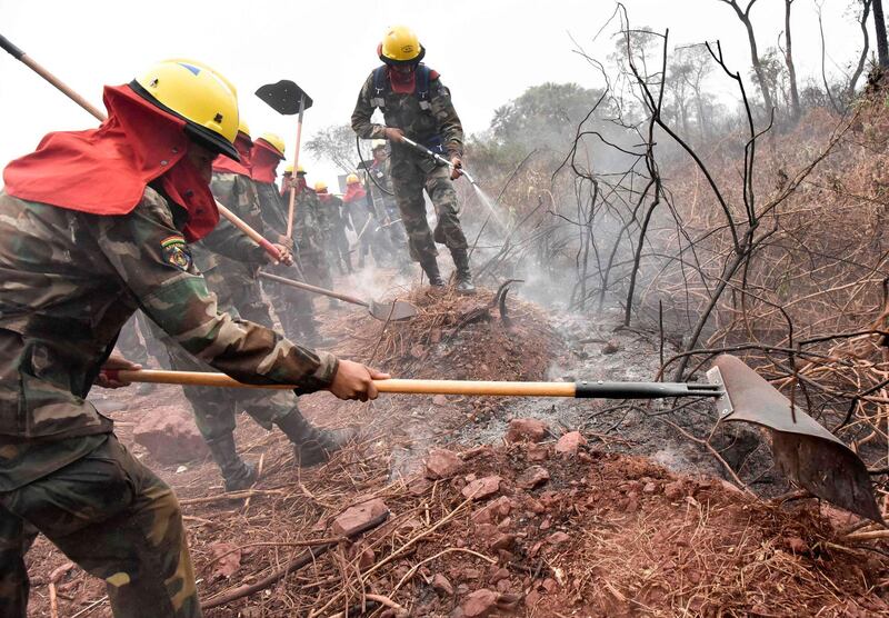 Bolivian soldiers combat forest fires in Otuquis National Park, in the Pantanal ecoregion of southeastern Bolivia, on August 26, 2019.  Like his far right rival President Jair Bolsonaro in neigboring Brazil, Bolivia's leftist leader Evo Morales is facing mounting fury from environmental groups over voracious wildfires in his own country. While the Amazon blazes have attracted worldwide attention, the blazes in Bolivia have raged largely unchecked over the past month, devastating more than 9,500 square kilometers (3,600 square miles) of forest and grassland. / AFP / Aizar RALDES
