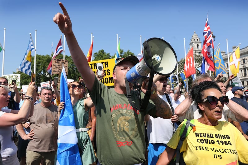 Protesters shout anti-government slogans at the Houses of Parliament from Parliament Square at an anti-lockdown protest in London.