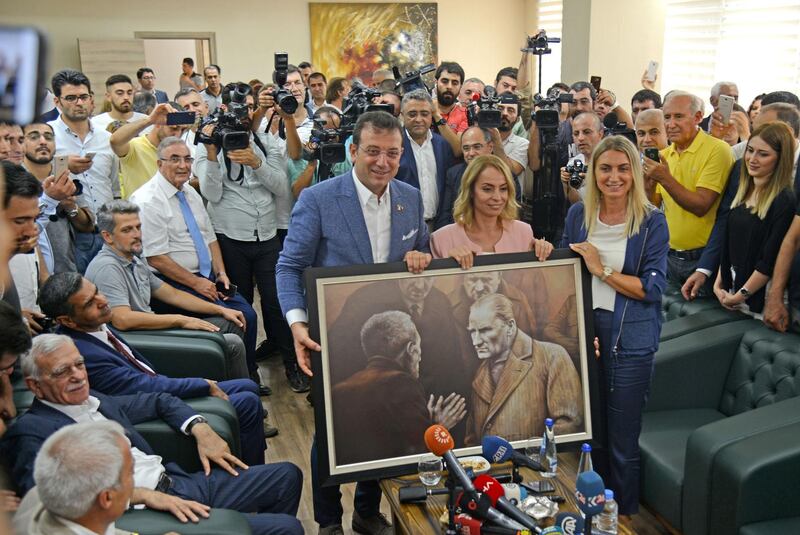 TOPSHOT - Ekrem Imamoglu (C,R), the new Mayor of Istanbul from Turkey's main opposition Republican People's Party (CHP) poses with a picture of modern Turkey founder Mustafa Kemal Ataturk he brings as a gift for the removed mayor of Diyarbakir, Adnan Selcuk Mizrakli (not pictured) during his visit on August 31, 2019, in Diyarbakir.  The mayors of Diyarbakir, Mardin and Van provinces in eastern Turkey -- all members of the pro-Kurdish Peoples' Democratic Party (HDP) elected in March -- were suspended over alleged ties to the outlawed Kurdistan Workers' Party (PKK). / AFP / Ilyas AKENGIN
