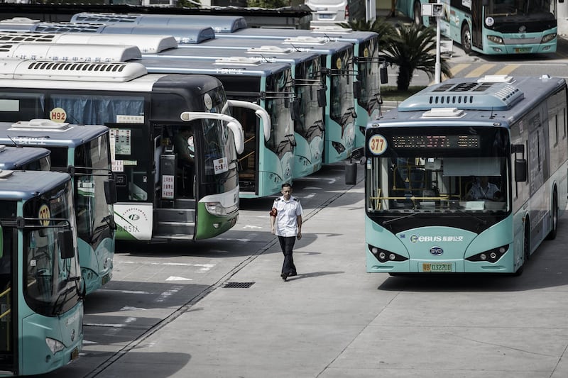 A worker walks while a BYD Co. electric bus arrives at a public transportation hub in Shenzhen, China, on Wednesday, Sept. 20, 2017. China, the world’s biggest auto market, may have all buses powered by batteries by 2020 and all other vehicles will follow suit by 2030, BYD Chairman Wang Chuanfu predicts. Photographer: Qilai Shen/Bloomberg