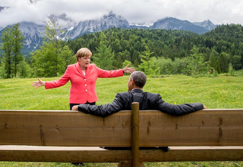 Angela Merkel talks to US President Barack Obama, who sits on a bench facing the Wetterstein mountains during a G7 meeting at Elmau Castle in Elmau, Germany, June 8, 2015. EPA