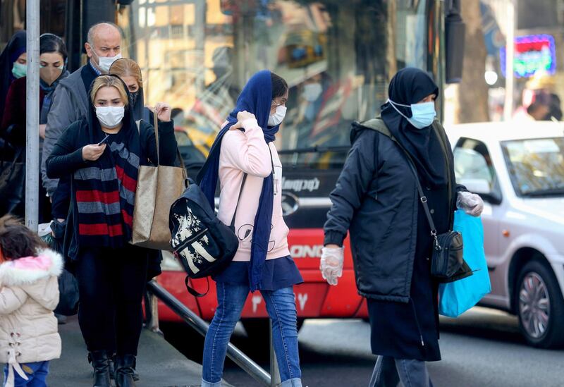 Iranians wearing protective masks amid the COVID-19 pandemic, leave a bus in the capital Tehran, on December 30, 2020.  / AFP / ATTA KENARE
