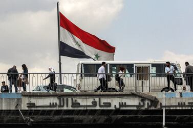 People cross the Hafez Al Assad bridge over the Barada river, named after the father of Syrian President Bashar Al Assad, in central Damascus on April 14, 2024.  AFP