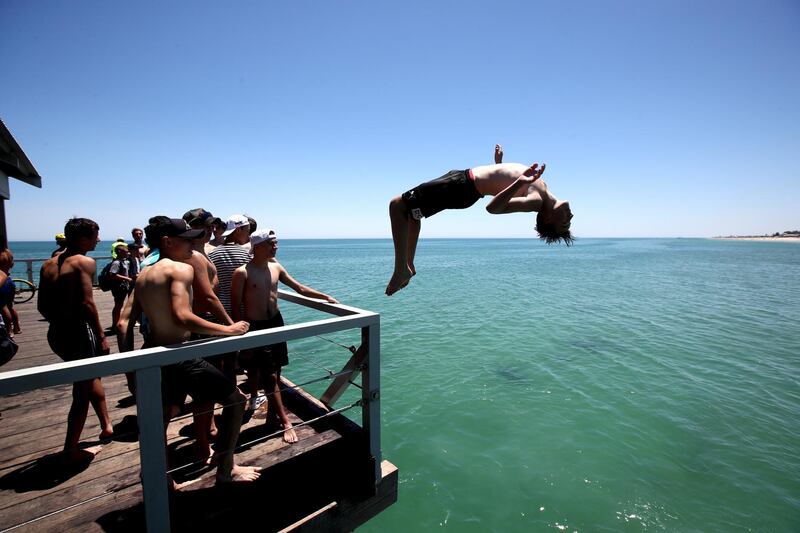 A teenager leaps from the Henley Beach Jetty during a hot day in Adelaide, Australia. EPA