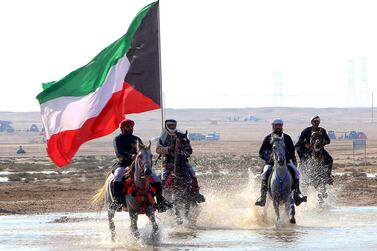 Members of Kuwaiti knights team carry a national flag as they perform with their horses on the sea side. AFP