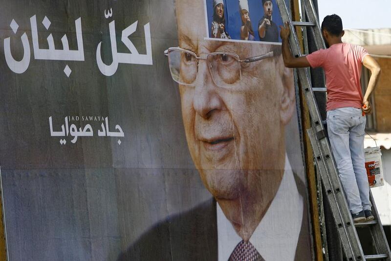A worker hangs a billboard showing Michel Aoun with Arabic words that reads "For all Lebanon," in the southern port city of Sidon, Lebanon. Mohammed Zaatari / AP Photo