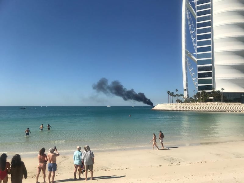 Beach-goers look on with concern as smoke billows from the ship. The National