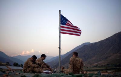 FILE - In this Sept. 11, 2011 file photo, US soldiers sit beneath an American flag just raised to commemorate the tenth anniversary of the 9/11 attacks at Forward Operating Base Bostick in Kunar province, Afghanistan. After 20 years of military engagement and billions of dollars spent, NATO and the United States still grapple with the same, seemingly intractable conundrum â€” how to withdraw troops from Afghanistan without abandoning the country to even more mayhem. (AP Photo/David Goldman, File)