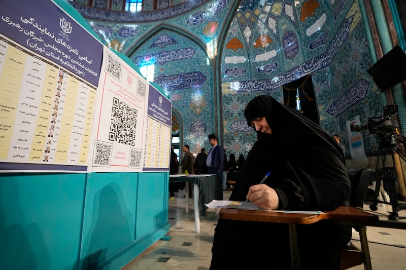 A voter fills out her ballot at a polling station in Tehran. AP