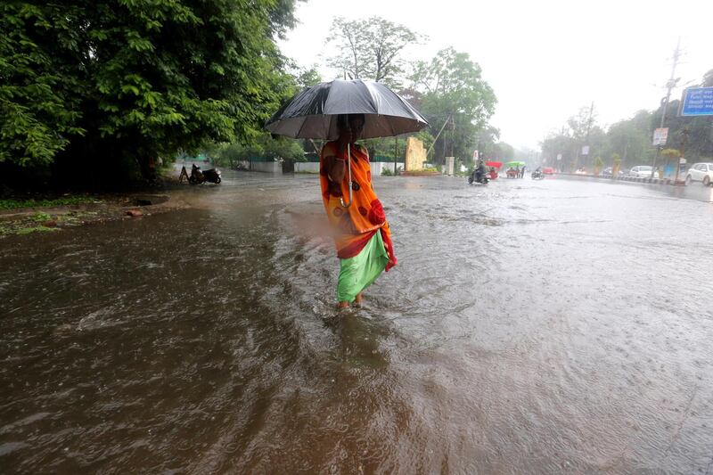 epa07727767 An Indian woman walks on a water logged street during heavy monsoon rain in Bhopal, India, 19 July 2019. Following a long period of hot dry weather, the showers are mostly welcomed by locals as they bring a temporary relief from the recent heat.  EPA/SANJEEV GUPTA