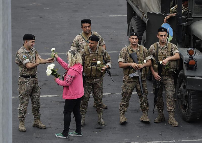 A Lebanese protester distributes roses to soldiers deployed in the area of Jal el-Dib during an anti-government demonstration in the northern outskirts of the Lebanese capital Beirut. AFP