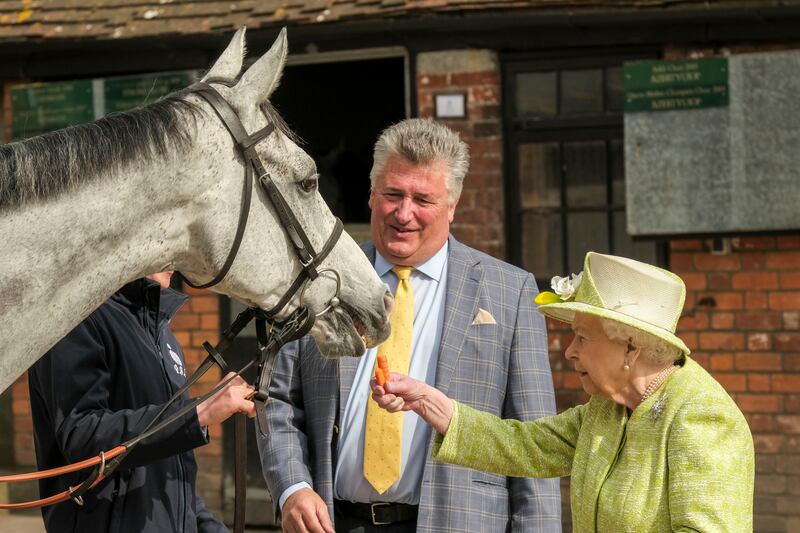 Queen Elizabeth II feeds a carrot to the horse Politologue, as trainer Paul Nicholls looks on, during a visit to Manor Farm Stables on March 28, 2019 in Ditcheat, UK. Getty Images