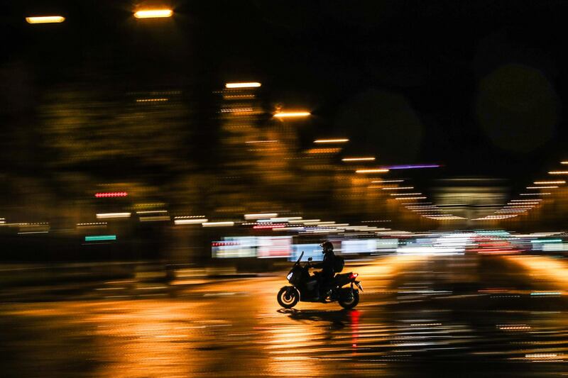 A slow shutter speed picture showing a man riding a motorcycle at the beginning of the night-time curfew, next to Arc de Triomphe in Paris, France.  EPA