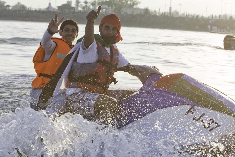 Two young men on jet ski at a boat parade marking the 42nd UAE National Day in Fujairah. Jaime Puebla / The National 