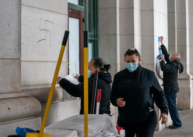 A cleaning crew covers hand-drawn swastikas on the front of Union Station. AP