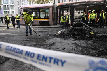 DUBLIN, IRELAND - NOVEMBER 24: Workers clean up the debris of a burnt train behind police cordon tape on November 24, 2023 in Dublin, Ireland. Vehicles were set alight set and shops looted in Dublin last night, following a knife attack outside a school that left five people, including three children, injured. (Photo by Charles McQuillan / Getty Images)