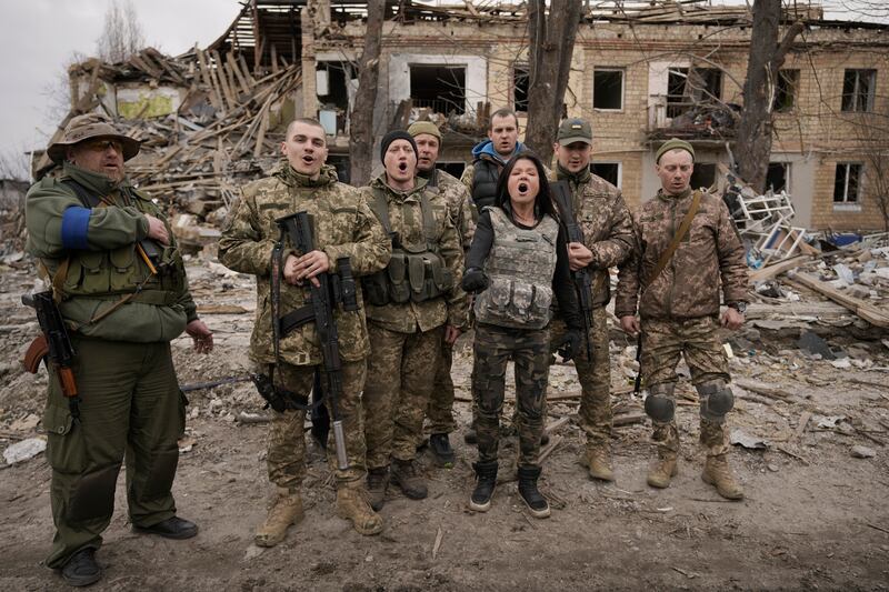 Ukrainian servicemen sing a patriotic song in front of buildings destroyed by Russian forces in Borodyanka. AP