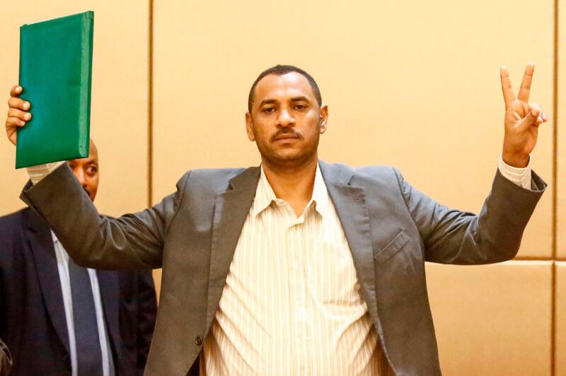 Protest leader Ahmed Rabie flashes the V sign for victory after signing the constitutional declaration with Sudan's deputy head of the Transitional Military Council, at a ceremony attended by African Union and Ethiopian mediators in the capital Khartoum on August 4, 2019. Sudan's army rulers and protest leaders today inked a hard-won constitutional declaration, paving the way for a promised transition to civilian rule. The agreement, signed during a ceremony witnessed by AFP,  builds on a landmark power-sharing deal signed on July 17 and provides for a joint civilian-military ruling body to oversee the formation of a transitional civilian government and parliament to govern for a three-year transition period. 
 / AFP / ASHRAF SHAZLY
