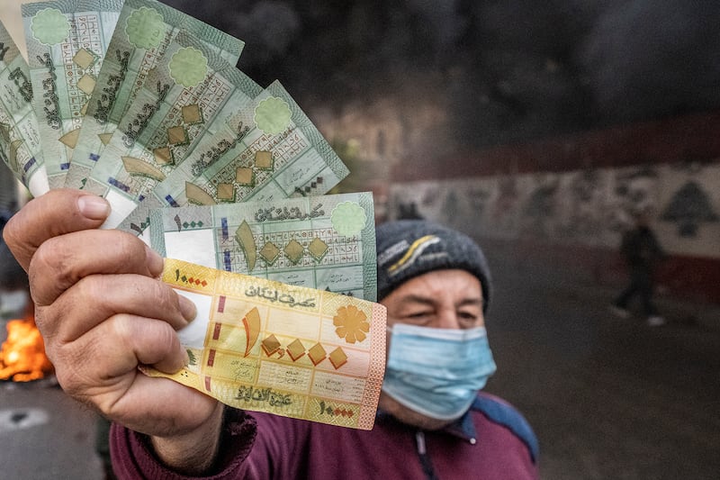 A protester brandishes a handful of Lebanese currency, which has become virtually worthless, outside the Central Bank. AP
