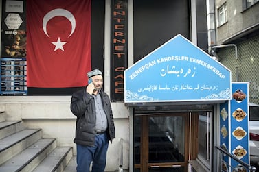 An Uighur man talks on the phone in front of a Uighur restaurant. Kerem Uzel for The National