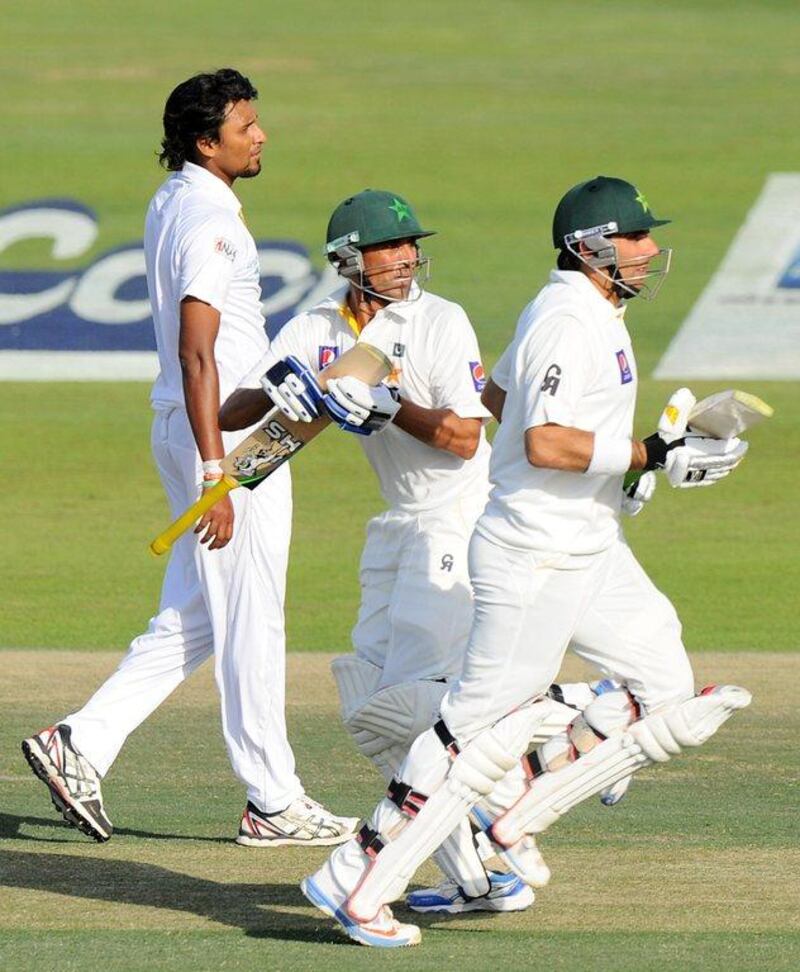 Pakistan batsman Younis Khan, centre, and Misbah-ul-Haq, right, run between the wickets as Sri Lankan bowler Suranga Lakmal looks on during the second day of their first cricket Test match at the Sheikh Zayed Stadium in Abu Dhabi on Wednesday. AFP PHOTO/Ishara S. KODIKARA