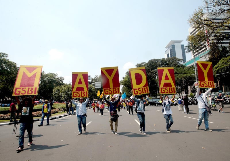 Indonesians hold placards as they march along a road toward the Presidential Palace in Jakarta. Bagus Indahono / EPA