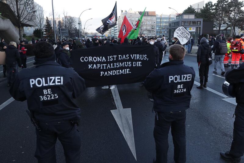 epa08911336 People holding a placard reading 'Corona is the virus, capitalism is the pandemic’ during a demonstration 'FCK2020 - For a better tomorrow' in Berlin, Germany, 30 December 2020. Protesters are against coronavirus conspiracy ideologues and for dignified health, a fair education, labor rights and labor protection.  EPA/HAYOUNG JEON